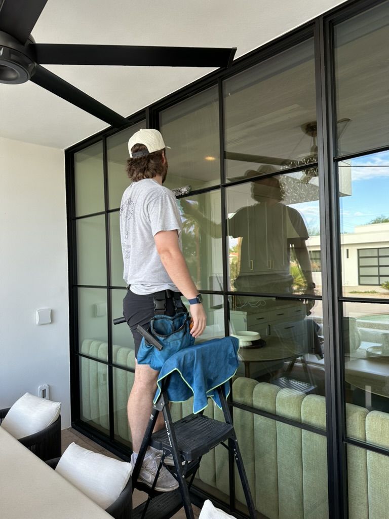 Tyler cleaning a floor-to-ceiling steel-frame window