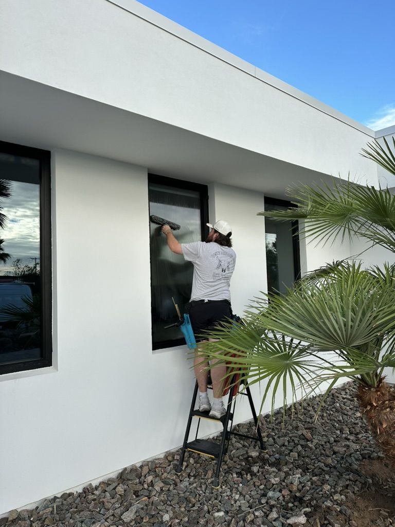 Tyler on a step ladder cleaning an exterior window